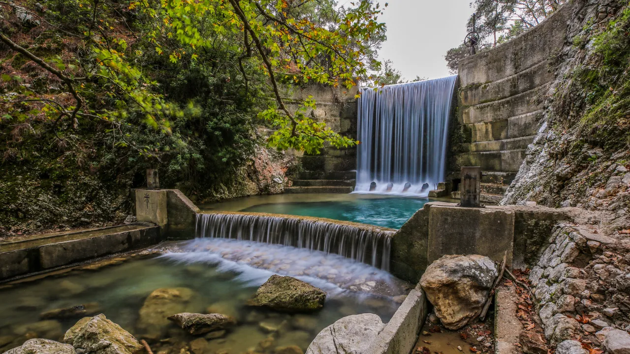 Een grote waterval en een kleine achter elkaar in een bos met rotsen aan de zijkant op Rhodos