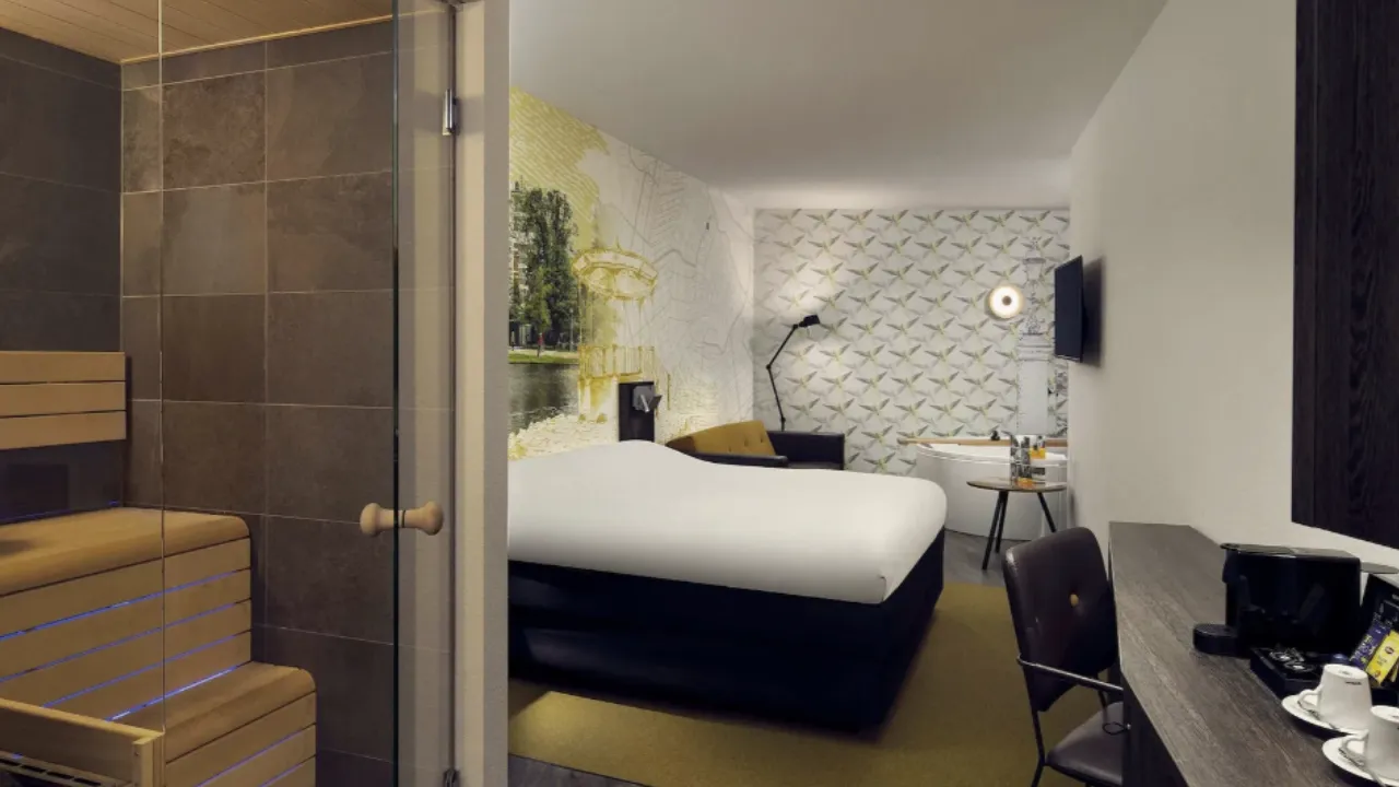 Sauna in hotelkamer met sauna en bruin/groene details in slaapgedeelte in hotelkamer van Inntel Hotels Amsterdam Centre