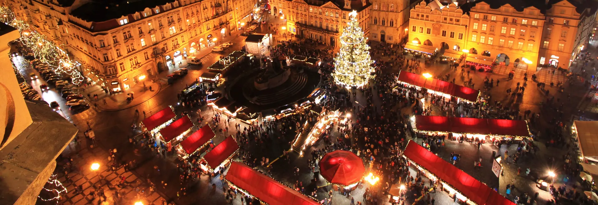 Groot plein met verlichte kerstkraampjes en grote verlichte kerstboom