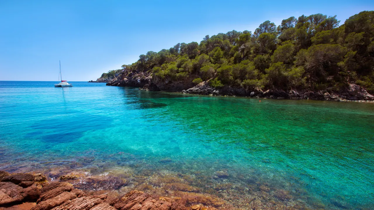 Rotsachtig strand en groenblauwe zee bij Santa Eulalia op Ibiza