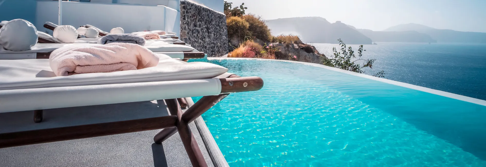 Zwembad met uitzicht over de zee en links ligbedjes met handdoeken