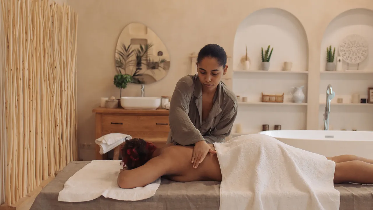 Vrouw die andere vrouw masseert in een wellness setting