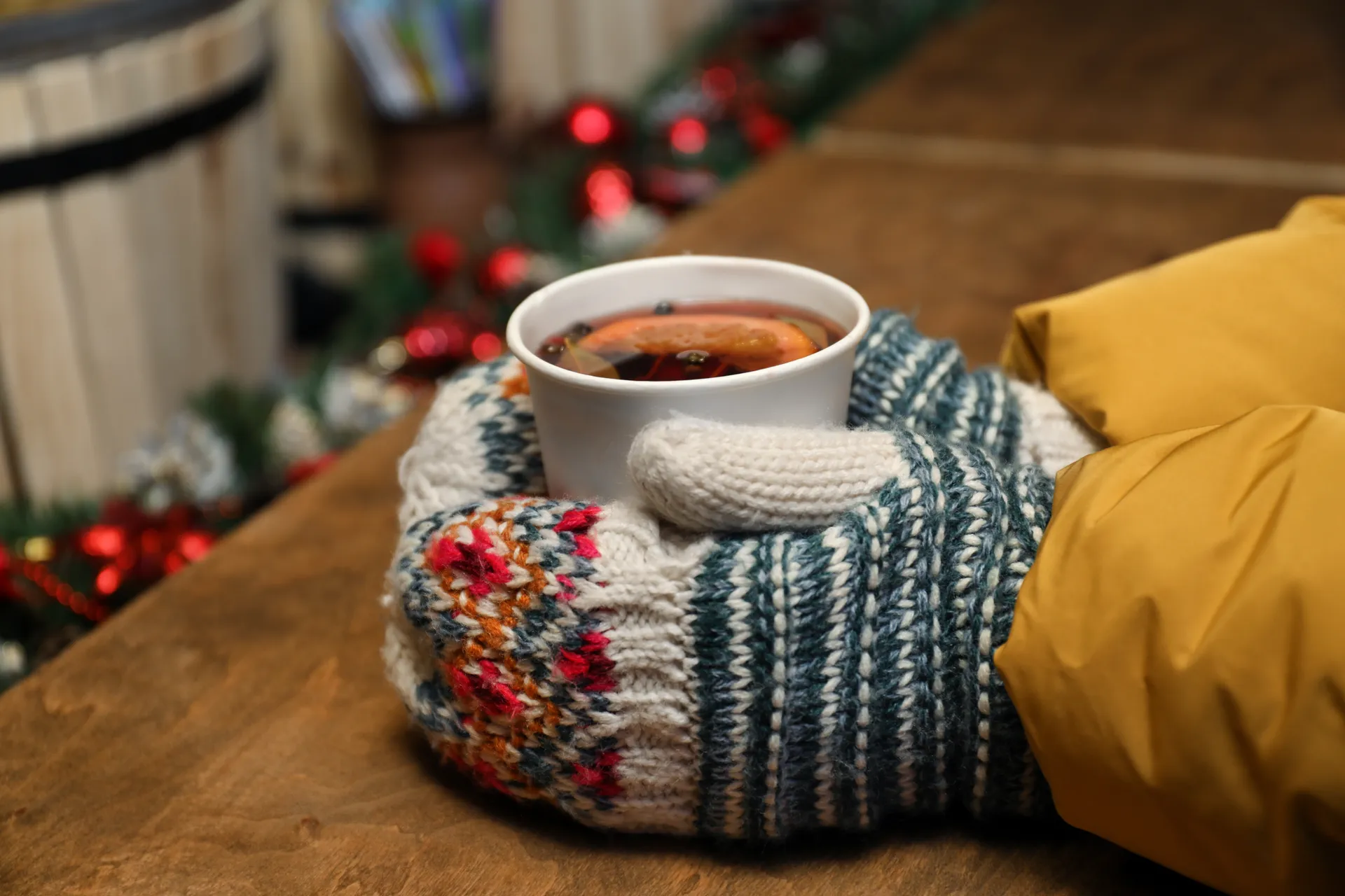 Handen met handschoenen om een kop met gluhwein heen