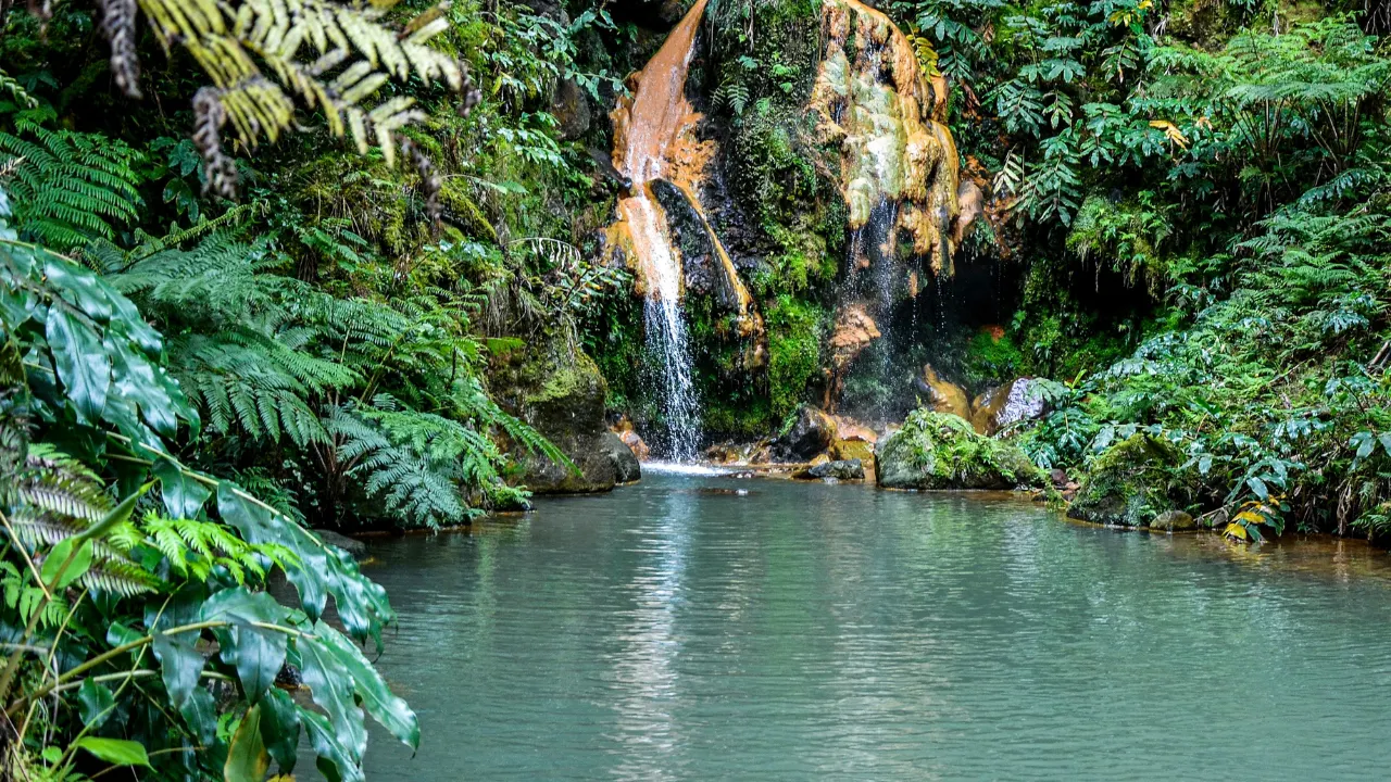 Waterval die uitmondt in meer met groen begroeide omgeving 