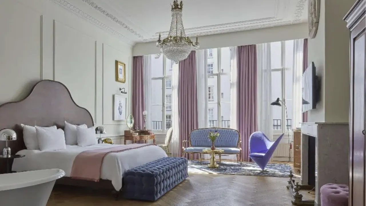 Slaapkamer in Pulitzer Amsterdam met kroonluchter aan plafond en roze/paarse details in kamer