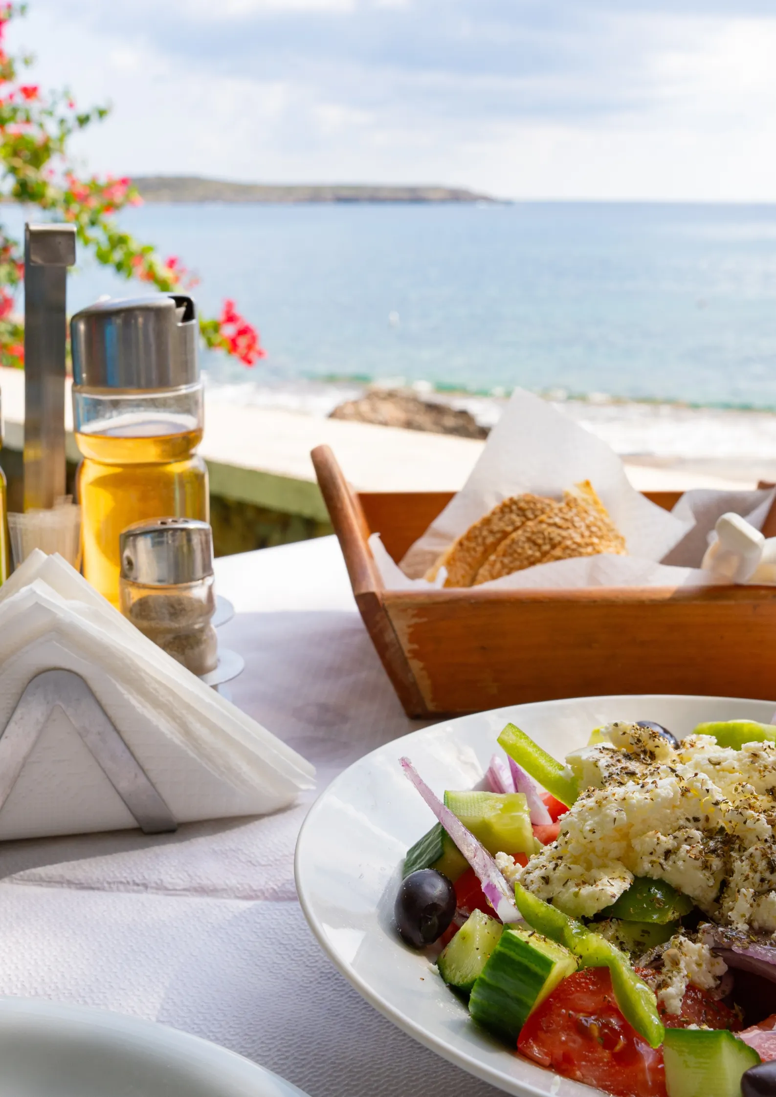 Griekse salade en brood op een gedekte tafel met de zee op de achtergrond