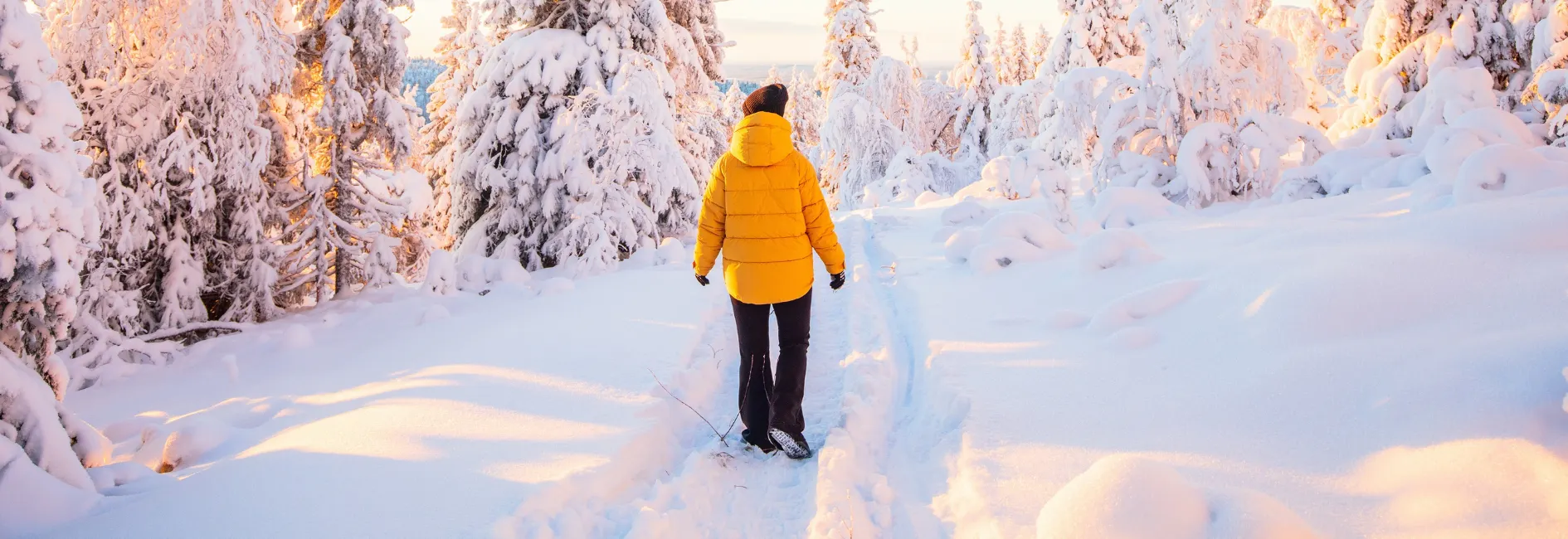 Persoon in besneeuwd landschap met gele jas aan