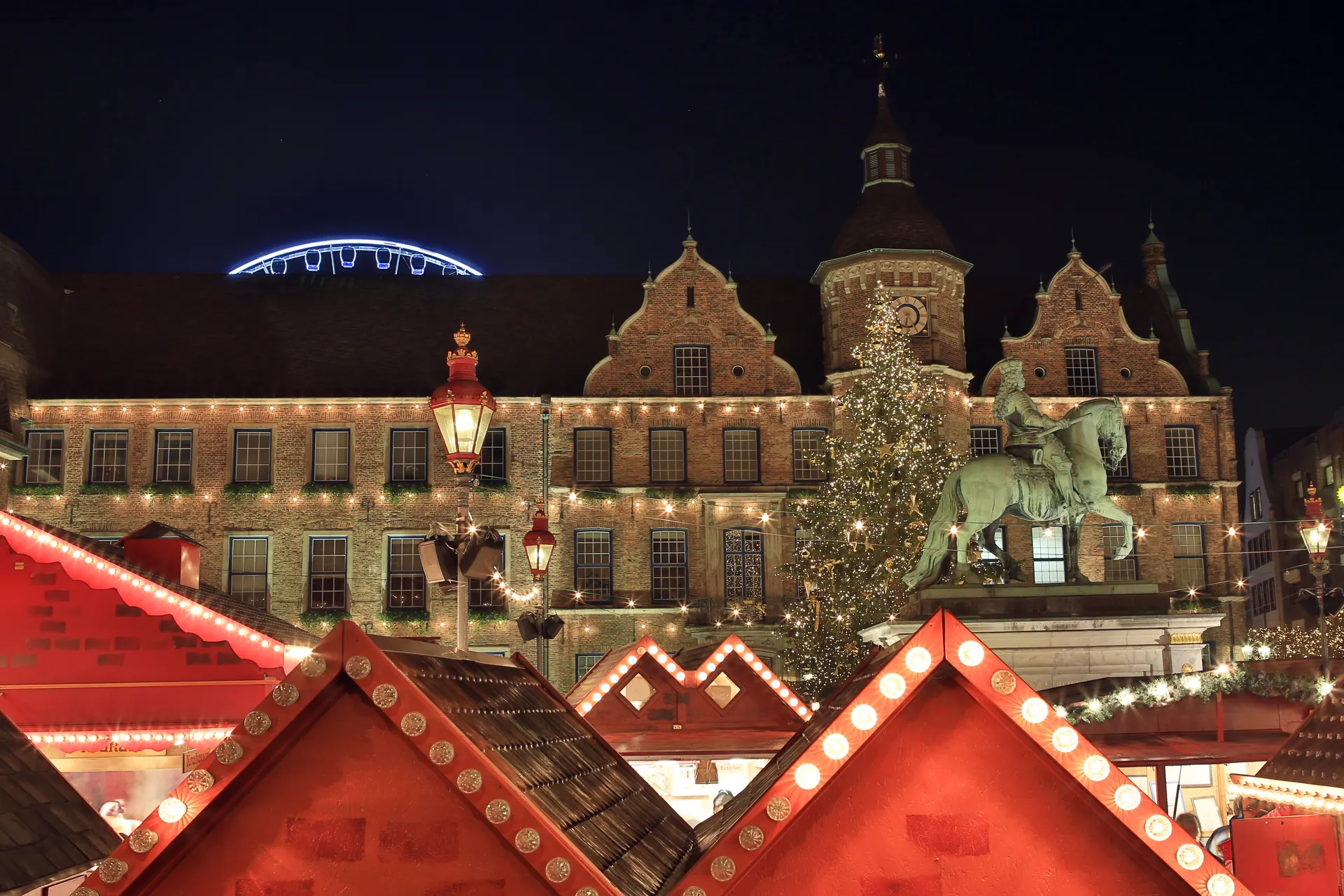 Plein met historische gebouwen, standbeeld en reuzenrad op achtergrond
