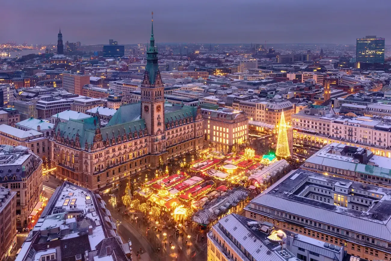 Bovenaanzicht van een plein met kerstmarkt met daar omheen gebouwen en een kerk