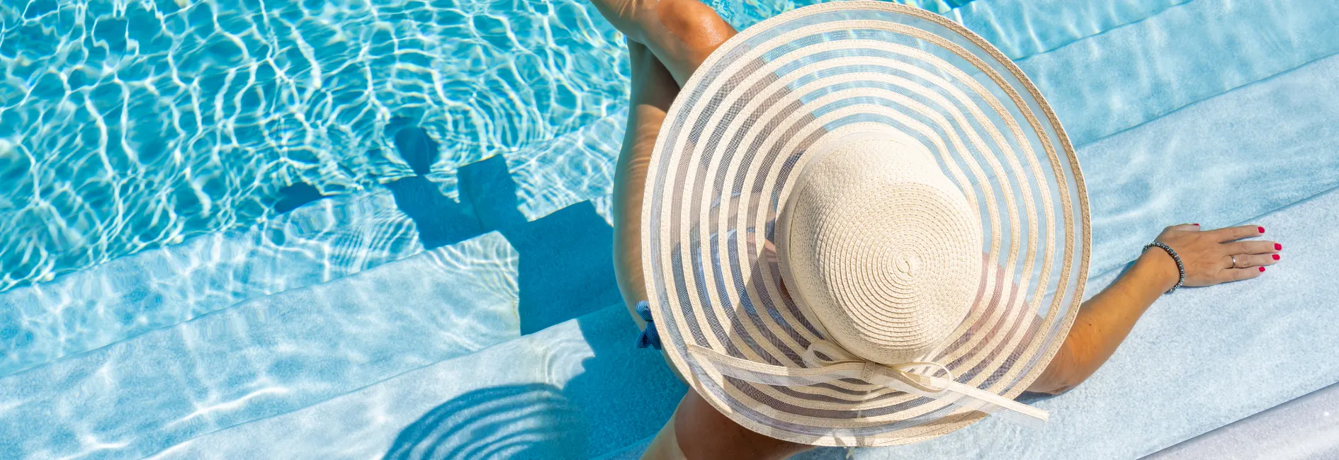 Vrouw met hoed die in een zwembad zit van vogelperspectief