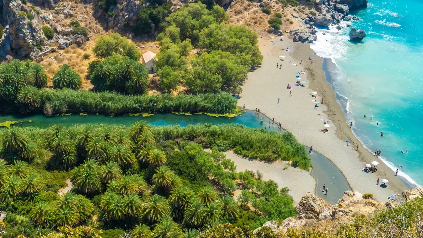Vogelperspectief op het strand van Preveli. Een rivier leidt door een palmbos naar het strand
