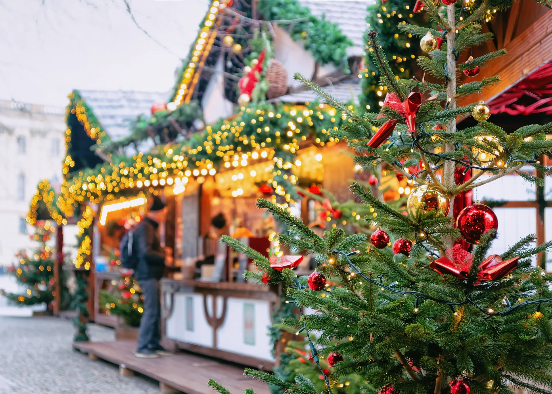 Kerstboom op de voorgrond met kerstkraampjes op de achtergrond