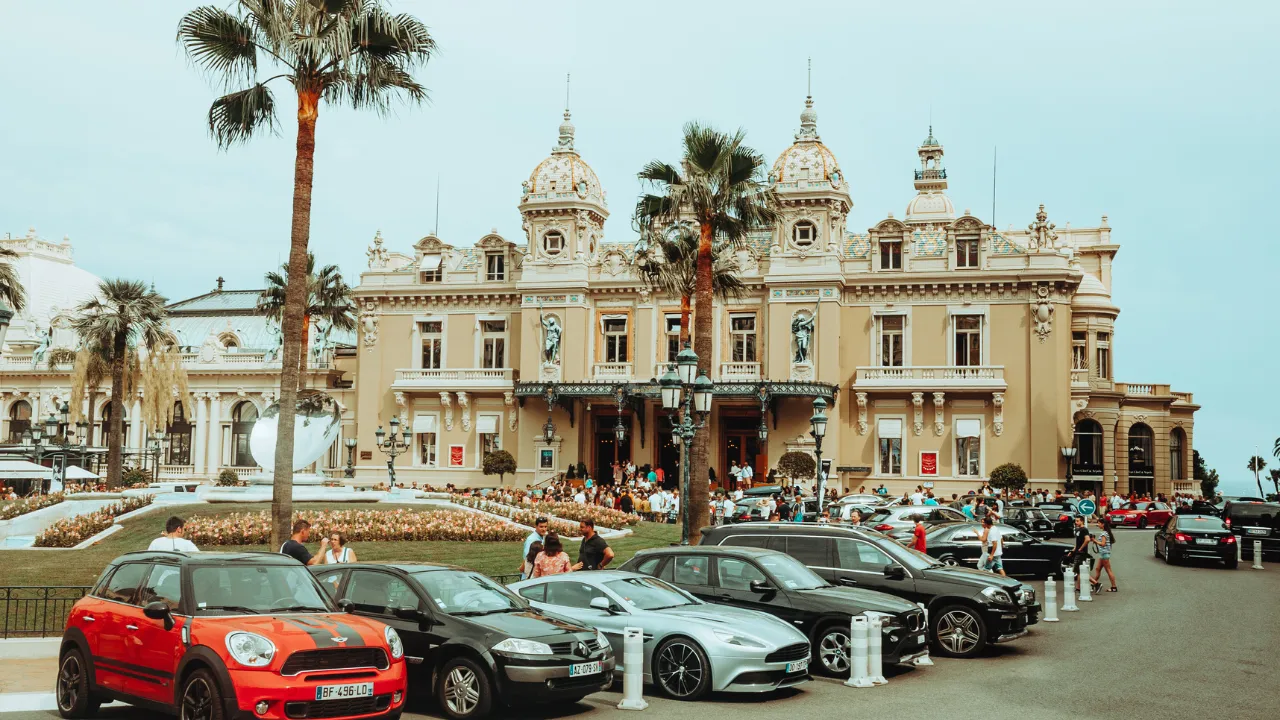 Gebouw met palmbomen en rij auto's voor de deur 