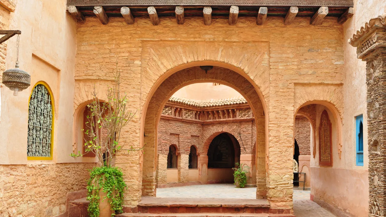 Arcade met gewelfde stenen boog en mozaïekramen in Sharm el Sheikh. Links hangt een oosterse lamp, vooraan een bloempot; rechts blauwe ramen.