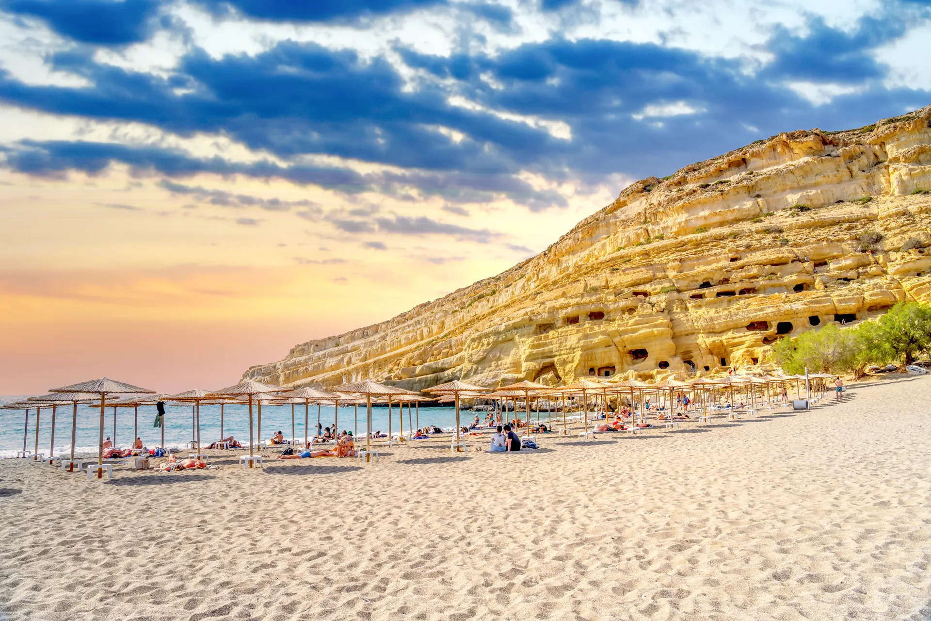 Grotten van Matala in de rotsen direct aan het strand met parasols