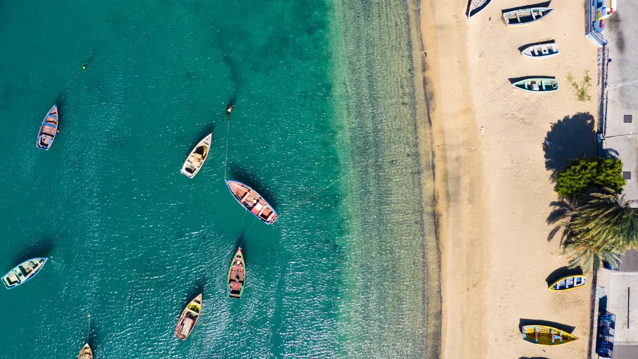 Vogelperspectief van strand rechts en links de zee met allemaal boten