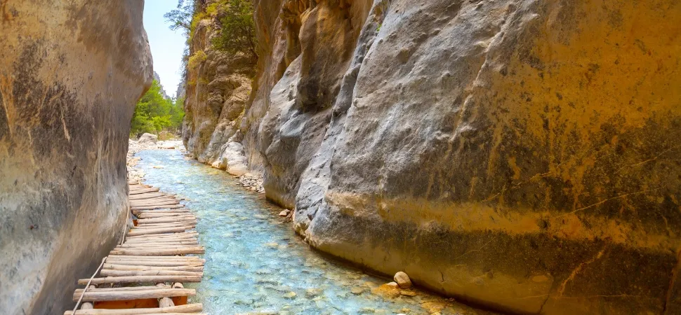 Houten loopbrug naast een beekje in een kloof op Kreta
